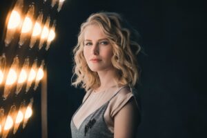 A blonde woman posing in front of lights.
