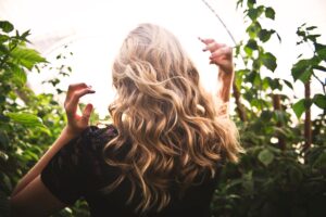 The back of a woman's hair in a greenhouse.