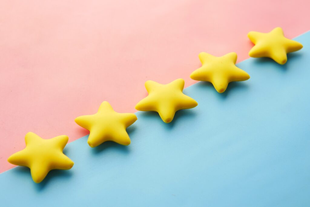 A row of yellow stars on a pink and blue background used for client selfie reviews.