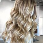 The back of a woman's hair with long wavy blonde hair.