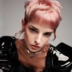 A woman with a pink pixie cut and black leather jacket.