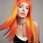A woman with long orange hair posing for a photo.