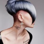 A woman with a grey shaved hair and tattoos.