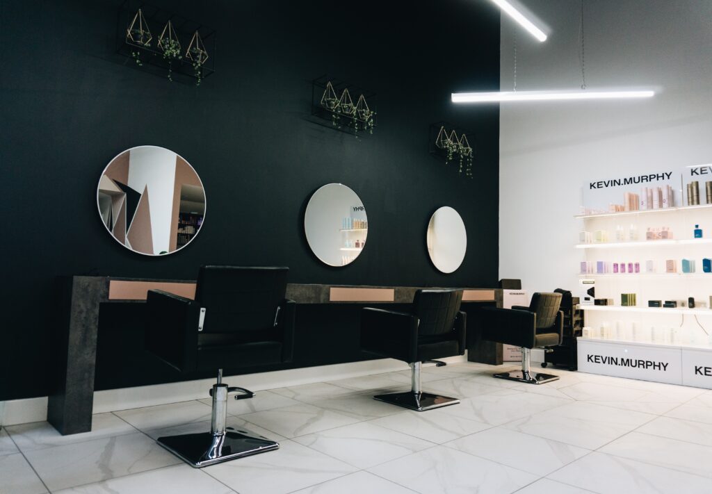 A hair salon listed in salon directories with a minimalist aesthetic featuring black walls and mirrors.