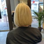 The back of a woman sitting in a chair in a salon.