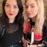 Two women posing for a photo in front of a brick wall.