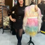A woman posing next to a colorful fur coat.