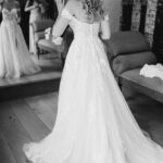 A bride getting ready in a wedding dress in front of a mirror.