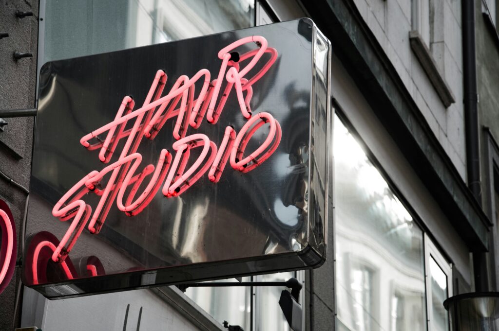 A neon sign reading "Hair Studio" in pink light glows vibrantly on the building exterior, hinting at one of the top 3 salons near me in Portsmouth.