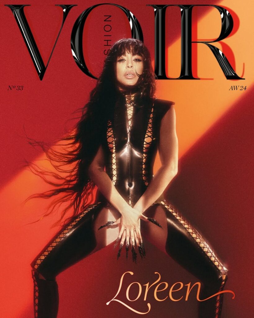 A woman in a black, form-fitting, laced outfit poses on the cover of Voir Fashion magazine, Issue No.33, Autumn/Winter 2024, with the name "Loreen" written below.