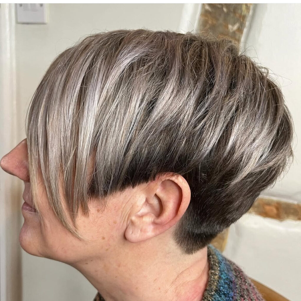 Side profile of a person with a short layered haircut, featuring dark brown underlayers and light blonde top layers, styled neatly.